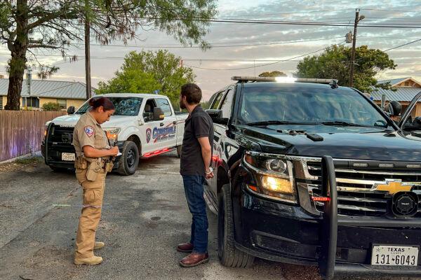 A Kinney County sheriff’s deputy arrests a suspected smuggler transporting several illegal immigrants from the U.S.–Mexico border to San Antonio, in Brackettville, Texas, on Aug. 26, 2022. (Charlotte Cuthbertson/The Epoch Times)