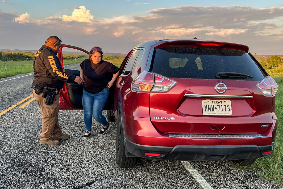 A Kinney County sheriff’s deputy arrests a woman for smuggling an illegal alien from the U.S.–Mexico border, through Kinney County, Texas, on Sept. 10, 2022. (Charlotte Cuthbertson/The Epoch Times)