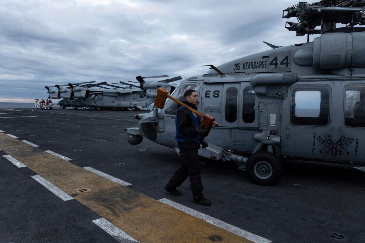 Deck personnel walks next to an MH-60S Seahawk on the flight deck of the Wasp-class amphibious assault ship USS Kearsarge (LHD 3), operating in the Baltic Sea on Sept. 2, 2022. (Michal Dyjuk/AP Photo)