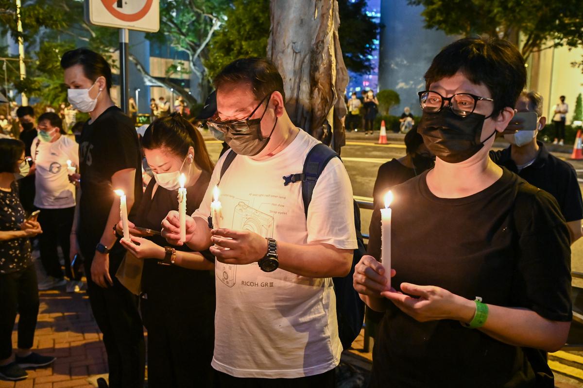 Members of the public mourn the passing of Queen Elizabeth II with flowers and candles outside the British Consulate General in Hong Kong on Sept. 19, 2022. (Sung Pi-lung/The Epoch Times)