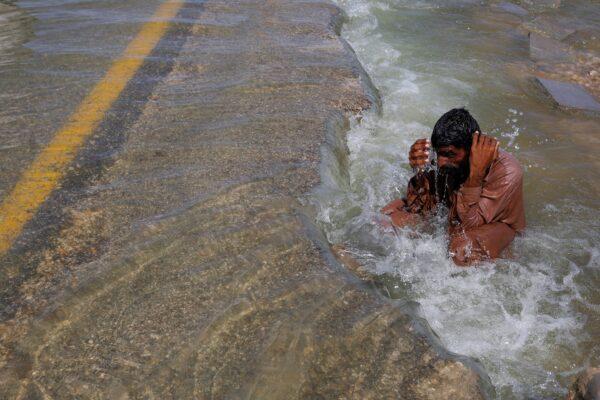 A displaced man cools off to avoid heat on a flooded highway following rains and floods during the monsoon season in Sehwan, Pakistan, on Sept. 16, 2022. (Akhtar Soomro/Reuters)