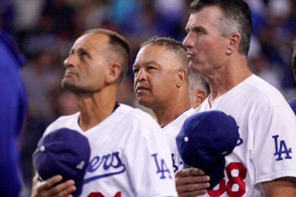 Los Angeles Dodgers manager Dave Roberts, center, stands with third base coach Dino Ebel, left, and coach Bob Geren as they watch a video tribute to Maury Wills, who passed away on Monday, prior to a baseball game against the Arizona Diamondbacks in Los Angeles, on Sept. 20, 2022. (Mark J. Terrill/AP Photo)