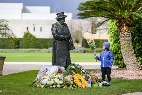 A 10-year-old boy places flowers at the base of a statue of Queen Elizabeth II after her passing at Government House in Adelaide, Australia, on Sept. 9, 2022. (Brenton Edwards/AFP via Getty Images)
