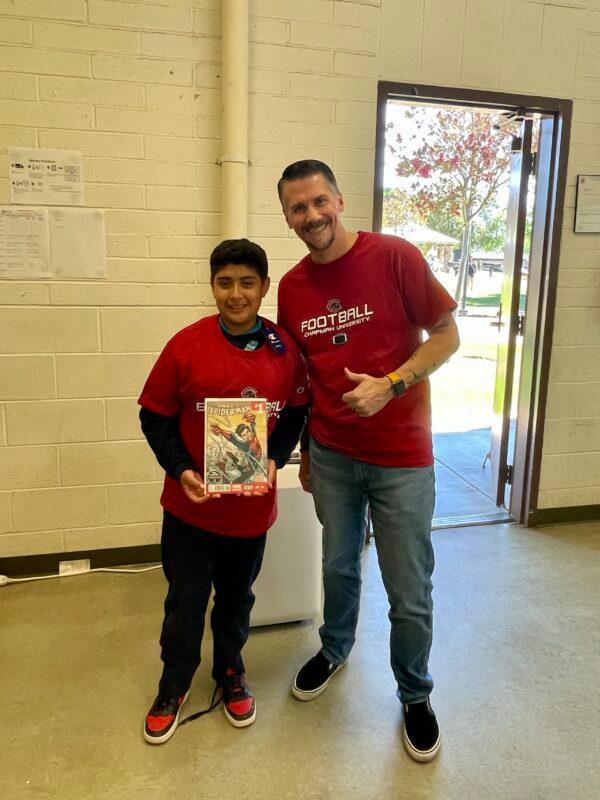 A boy receives a Spider Man comic book from a donor-turned-mentor of the Youth Centers of Orange in Orange, Calif. (Courtesy of the Youth Centers of Orange)