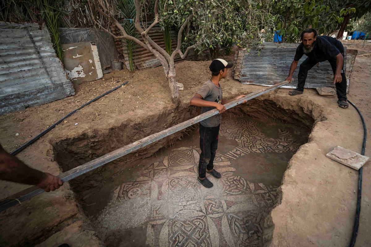 Palestinians clean around a Byzantine-era mosaic floor that was uncovered recently by a farmer in Bureij in central Gaza Strip, Sept. 5, 2022. (Fatima Shbair/AP Photo)
