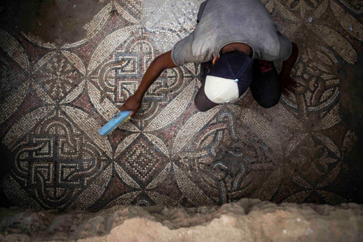 A Palestinian sweeps dust off parts of a Byzantine-era mosaic floor that was uncovered by a farmer in Bureij in central Gaza Strip, Sept. 5, 2022. (Fatima Shbair/AP Photo)