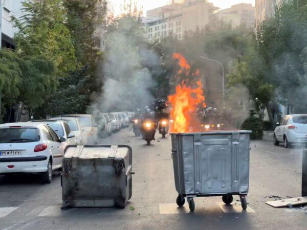 A trash bin is burning as anti-riot police arrive during a protest over the death of a young woman who had been detained for violating the country's conservative dress code, in downtown Tehran, Iran, on Sept. 20, 2022. (AP Photo)