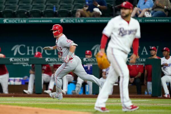 Los Angeles Angels' Mike Trout, left, sprints down the first base line on his way to a two-run double as Texas Rangers starting pitcher Martin Perez, right, looks to the outfield in the third inning of a baseball game in Arlington, Texas, Sept. 22, 2022. (Tony Gutierrez/AP Photo)