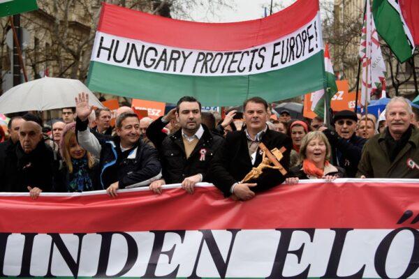 Demonstrators hold a flag in the colors of Hungary reading "Hungary protects Europe" as they arrive to listen to a speech by their prime minister in Budapest, Hungary, on March 15, 2018. (Attila Kisbenedek/AFP via Getty Images)