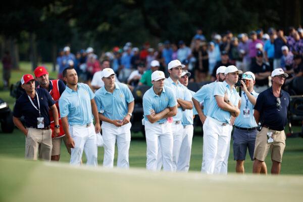 Xander Schauffele, Jordan Spieth, Sam Burns, Scottie Scheffler, Assistant Captain Fred Couples, Cameron Young and Justin Thomas of the U. S. Team watch as Max Homa and Tony Finau of the U.S. Team play the 18th green on day one of the 2022 Presidents Cup at Quail Hollow Country Club in Charlotte, N.C., on Sept. 22, 2022. (Jared C. Tilton/Getty Images)