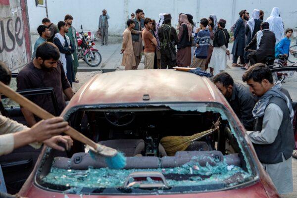 Afghan people clean a car that was damaged by an explosion, in Kabul, Afghanistan, on Sept. 21, 2022. (Ebrahim Noroozi/AP Photo)