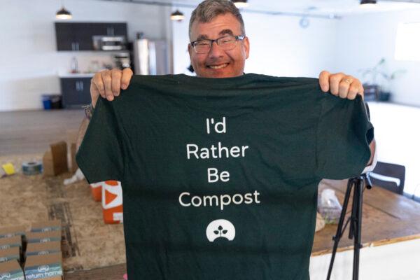 Return Home CEO Micah Truman holds up a T-shirt with the slogan “I’d rather be compost” on March 14, 2022. (Jason Redmond/AFP via Getty Images)