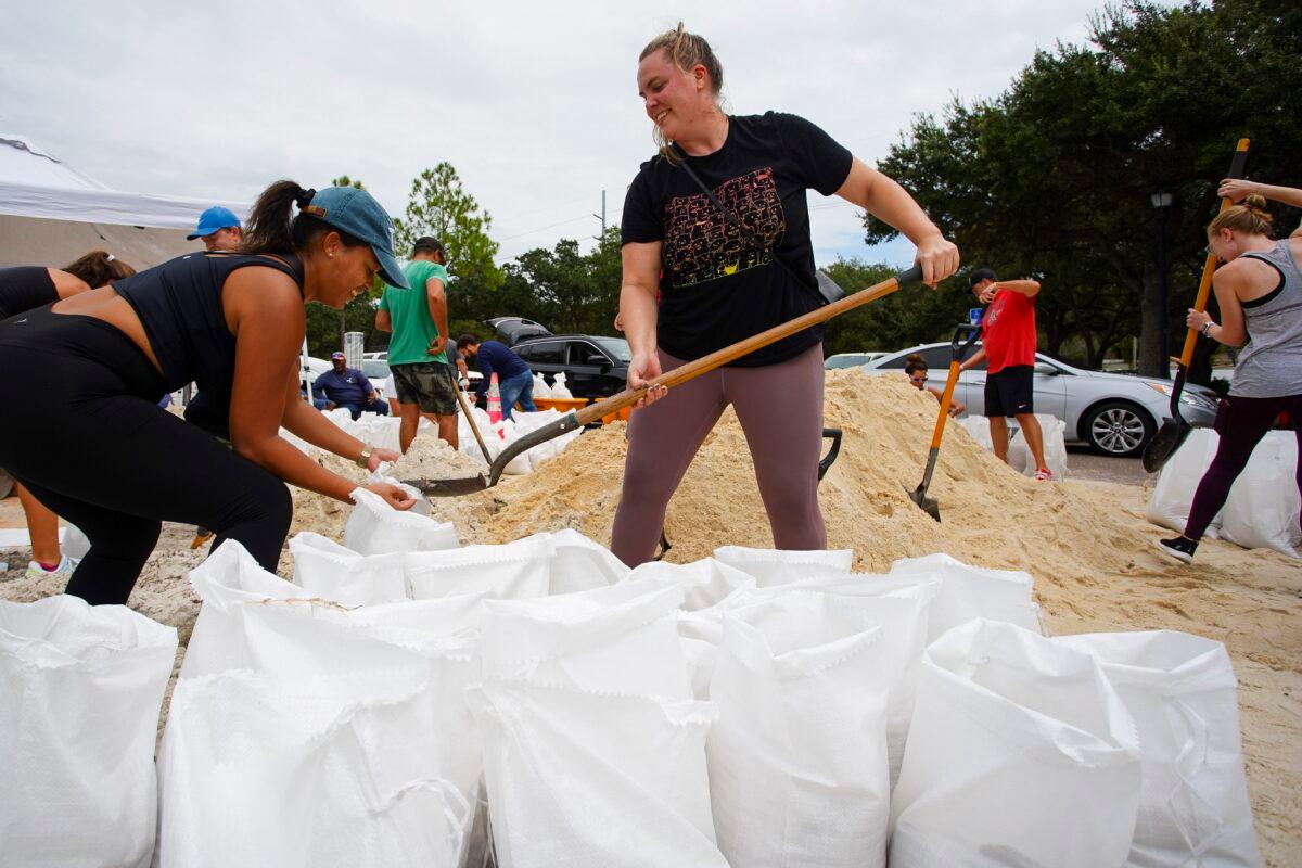  Friends Felicia Livengood, 29, and Victoria Colson, 31, fill sandbags along with hundreds of other Tampa, residents that waited for over 2 hours at Himes Avenue Complex to fill their 10 free sandbags in Tampa, Fla., on Sept. 25, 2022. (Luis Santana/Tampa Bay Times via AP)