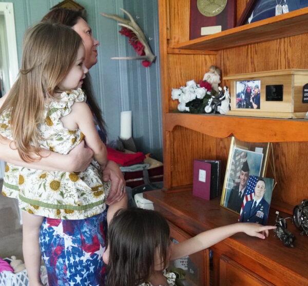 Nikki Jones holds 3-year-old Raven as they look at the memory shelf she made in her husband's memory, with 5-year-old Harley by her side in their Florida home, on Sept. 20, 2022. (Jann Falkenstern/The Epoch Times)