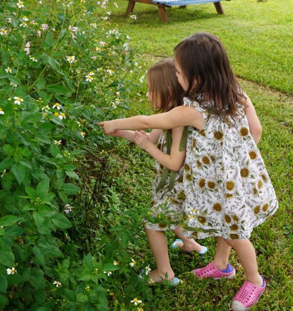 Raven, 3,  (left) and her sister Harley, 5,  look at a memory garden of wildflowers planted in their father's memory on Sept. 20, 2022. (Jann Falkenstern/The Epoch Times)