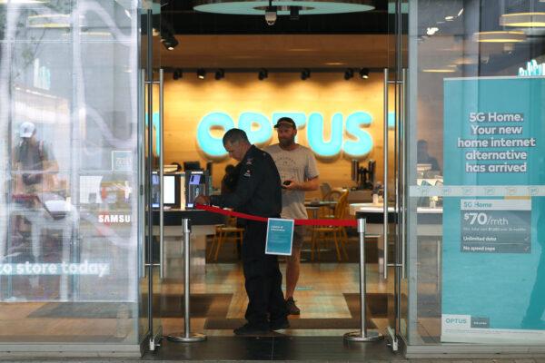 A security guard in an Optus retail store removes a barrier for a customer in Perth, Australia, on March 27, 2020. (Paul Kane/Getty Images)