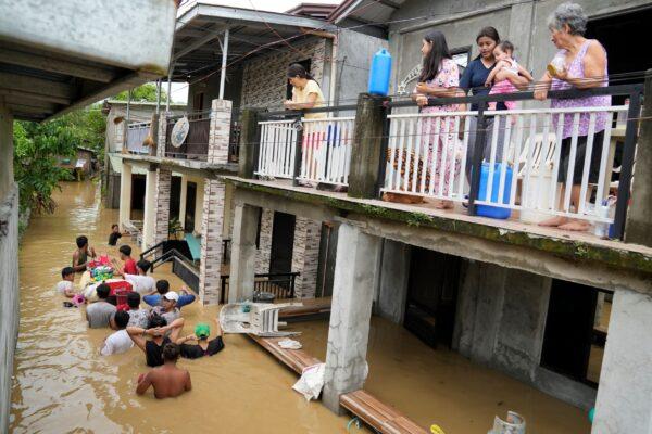 Residents stay on the deck of their house as others negotiate a flooded road due to Typhoon Noru in San Miguel town, Bulacan Province, Philippines, on Sept. 26, 2022. (Aaron Favila/AP Photo)