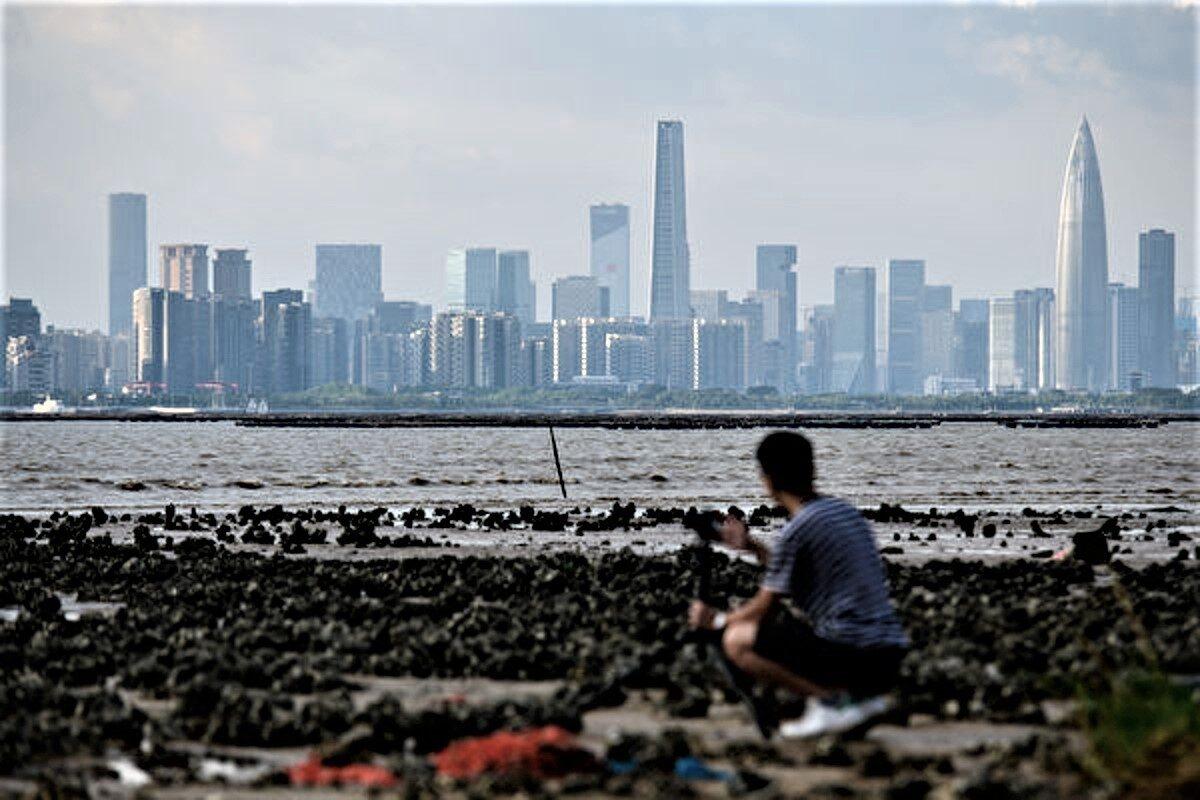 A man sets up his camera as he looks across Deep Bay toward the Chinese mainland city of Shenzhen's (back) skyline from Hong Kong on Sept. 12, 2018. (Anthony Wallace/AFP via Getty Images)