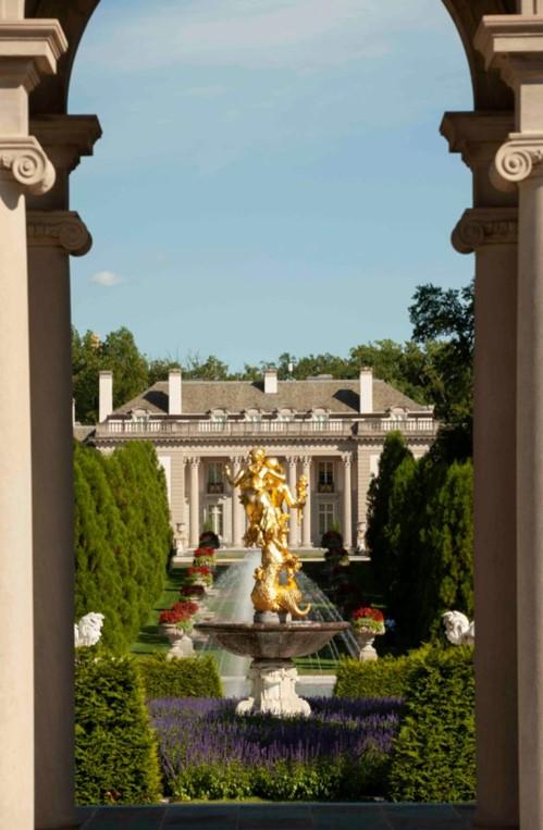 A view through the archway in the colonnade over the shoulder of the gilded sculpture Achievement by sculptor Henri Crenier as it looks toward the mansion. On either side of the sculpture are Carrara marble fountain sculptures of Triton, the god of the sea. The sculpture is surrounded by western arborvitae and crimson pygmy barberry. (J.H.Smith/Cartiophotos)