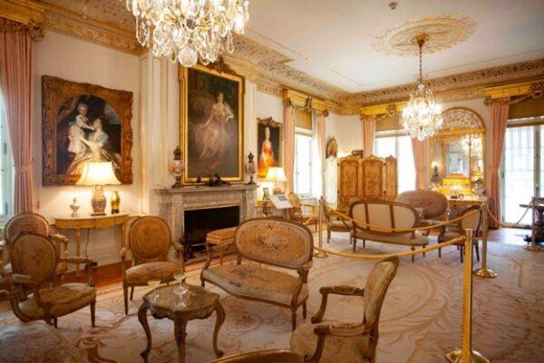 The drawing room offers aesthetic harmony and delight. Soft off-white paneled walls are masterfully adorned with gilded trim, marble mantels, and pastel curtains. Elegant curves grace the wall corners, ceiling cornices, and the legs of furnishings, creating a subtle sculptural effect. (J.H.Smith/Cartiophotos)