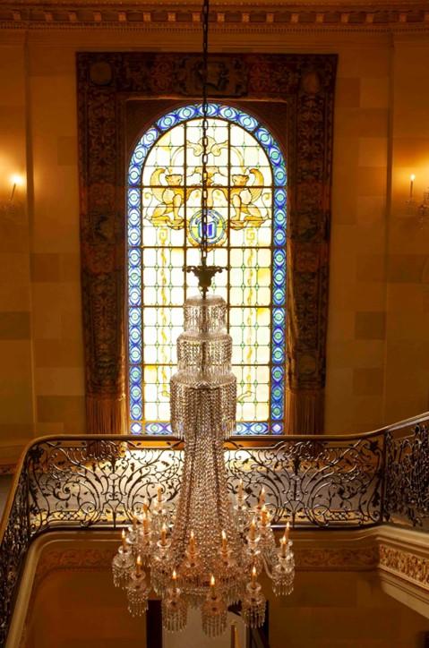 The central staircase is ornamented with an intricate and magnificent chandelier, surrounded by an elegant wrought-iron balustrade and illuminated by the natural light glowing through the stained glass window. (J.H.Smith/Cartiophotos)