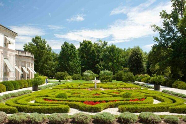 The mansion also enjoys a view over a formal French parterre side garden (garden beds arranged in an ornamental design) with symmetrically arranged patterns formed from boxwood hedges and red flowers in between as accents. A white stone pathway accentuates the patterns. (J.H.Smith/Cartiophotos)