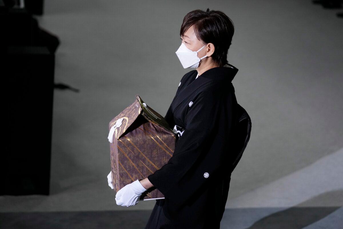 Akie Abe, wife of former Prime Minister Shinzo Abe, carries a cinerary urn containing his ashes at his state funeral in Tokyo on Sept. 27, 2022. (Franck Robichon/Pool photo via AP)