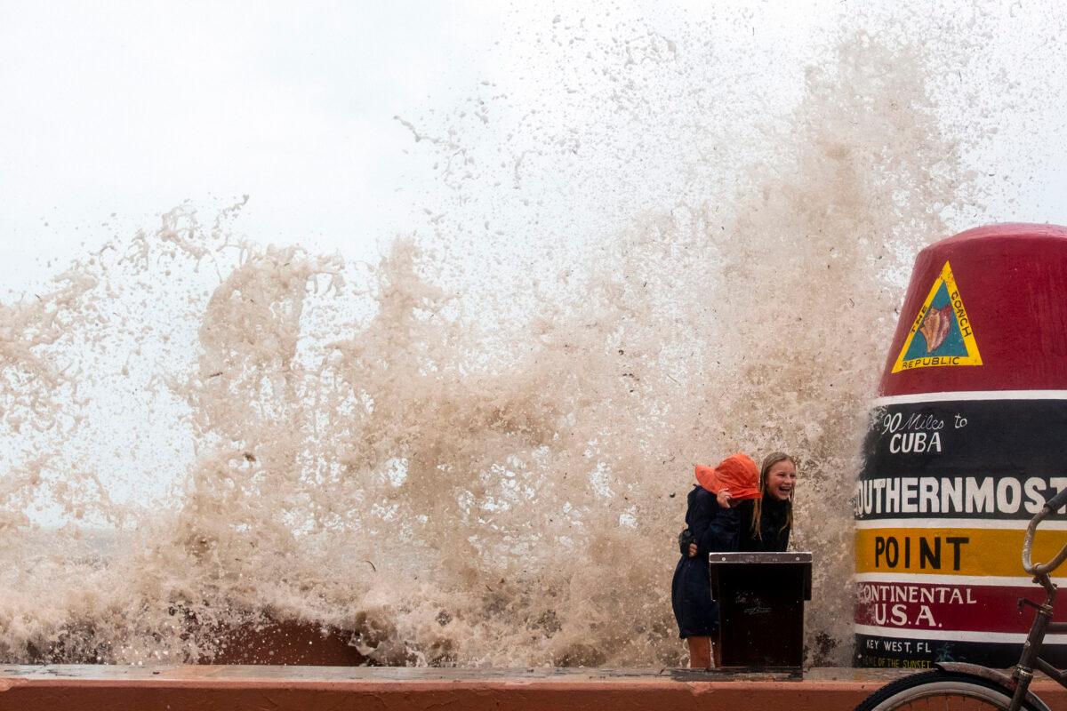 Visitors to the Southernmost Point buoy brave the high waves from Hurricane Ian crash for photos in Key West, Fla., on Sept. 27, 2022. (Mary Martin/AP Photo)