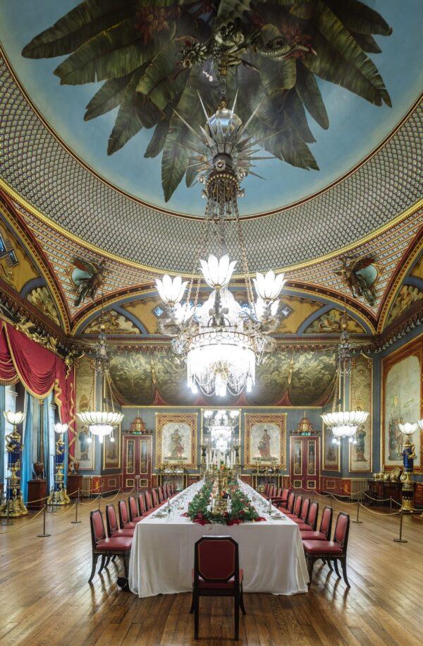 The spacious banquet room is the setting for many guests. Large candelabras on either side of the mahogany table light up an ornate silver gilt centerpiece. Canvas wall coverings and lamp stands are decorated with carved dragon mounts with lotus shades. The impressive central chandelier, embellished with six silver dragons breathing “fire,” hangs from a painted dome ceiling. Smaller chandeliers feature small birds inspired by Chinese mythology. (Brighton & Hove Museums)