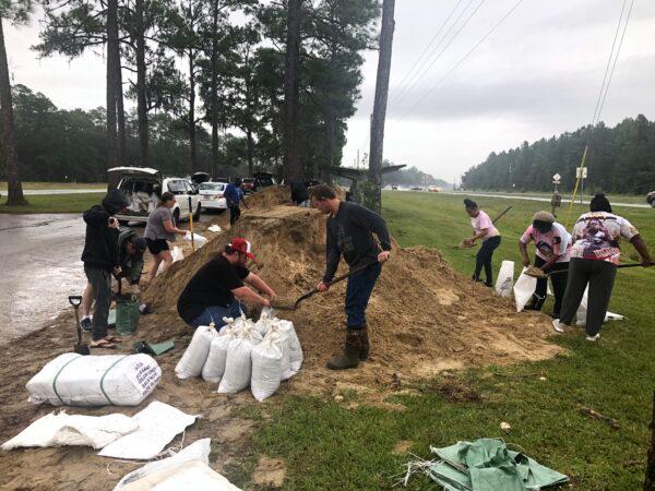 As the first rain from Hurricane Ian begins to fall in North Central Florida on Sept. 28, Alachua County residents fill sandbags at do-it-yourself stations using shovels brought from home. (Nanette Holt/The Epoch Times)
