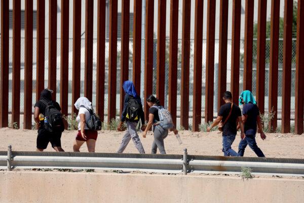 Migrants walk along the U.S. border fence to turn themselves in to U.S. Border Patrol after crossing the Rio Grande from Mexico in El Paso, Texas, on Sept. 21, 2022. (Joe Raedle/Getty Images)