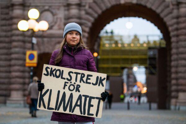 Swedish climate activist Greta Thunberg poses for a picture holding a sign reading "School strike for Climate" as she protests in front of the Swedish Parliament (Riksdagen) in Stockholm on Nov. 19, 2021. (Jonathan Nackstrand/AFP via Getty Images)