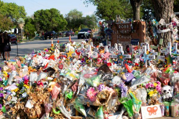 Weathered signs, candles, and stuffed animals remain at a memorial outside Robb Elementary School in Uvalde, Texas, on July 13, 2022. (Kaylee Greenlee Beal/Reuters)