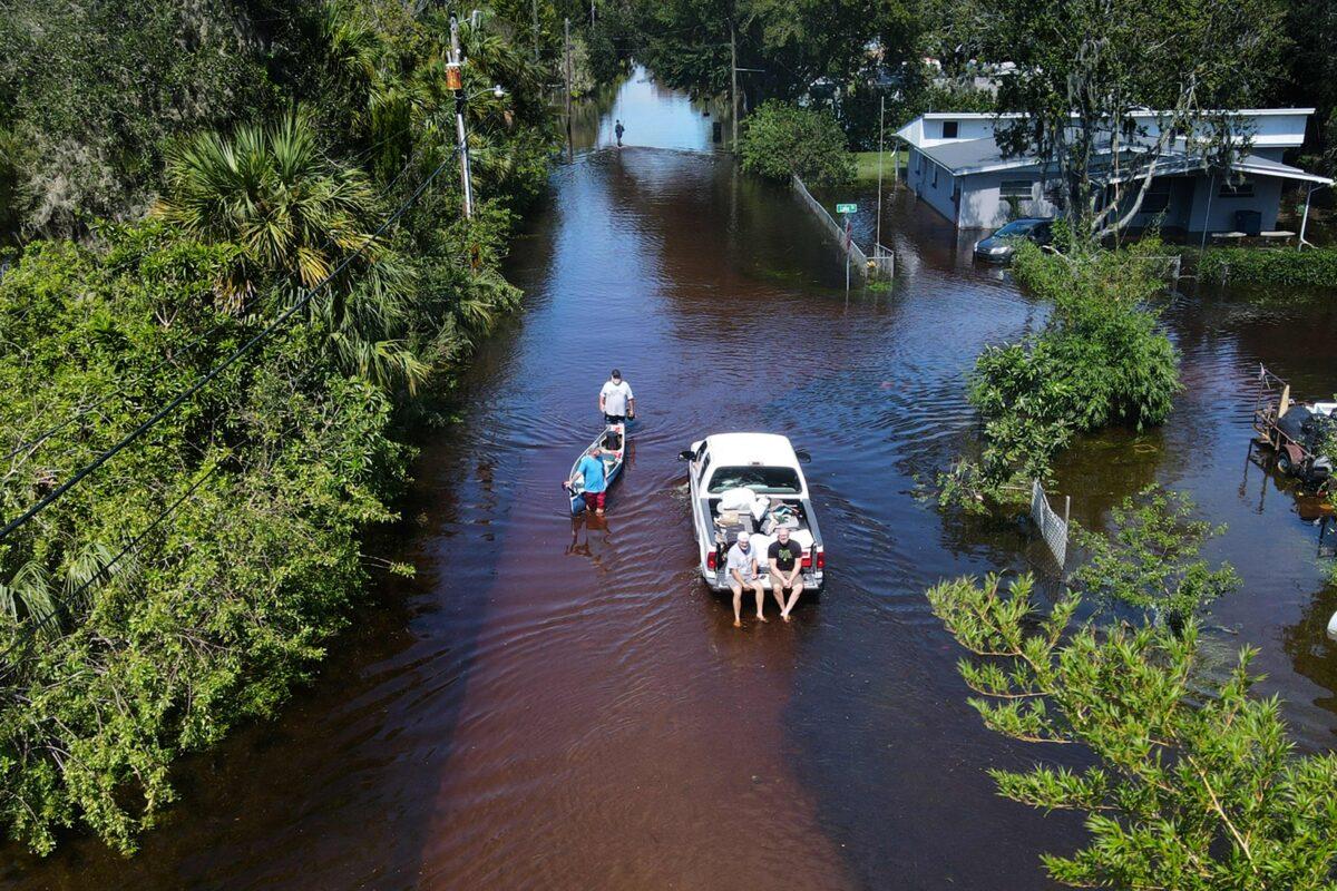 In this aerial view, a man tows a canoe through a flooded street of his neighborhood in New Smyrna Beach, Fla., on Sept. 30, 2022. (Jim Watson/AFP via Getty Images)