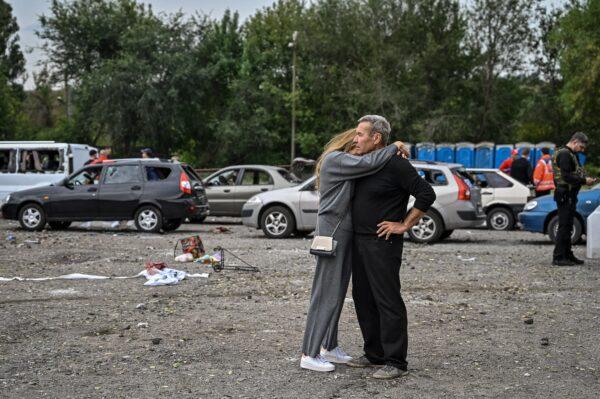 A couple hug each other near cars damaged by a missile strike on a road near Zaporizhzhia, Ukraine, on Sept. 30, 2022, amid the Russian invasion of Ukraine. (Genya Savilov/AFP)