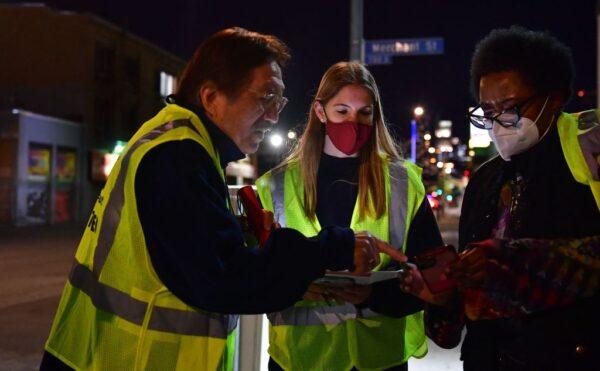 Volunteers Mike Murase (L), Jessica Margraf (C), and Kimberly Briggs look over a map of the neighborhood while walking the streets of downtown Los Angeles during the third night of the Greater Los Angeles Homeless Count in Los Angeles on Feb. 24, 2022. (Frederic J. Brown/AFP via Getty Images)