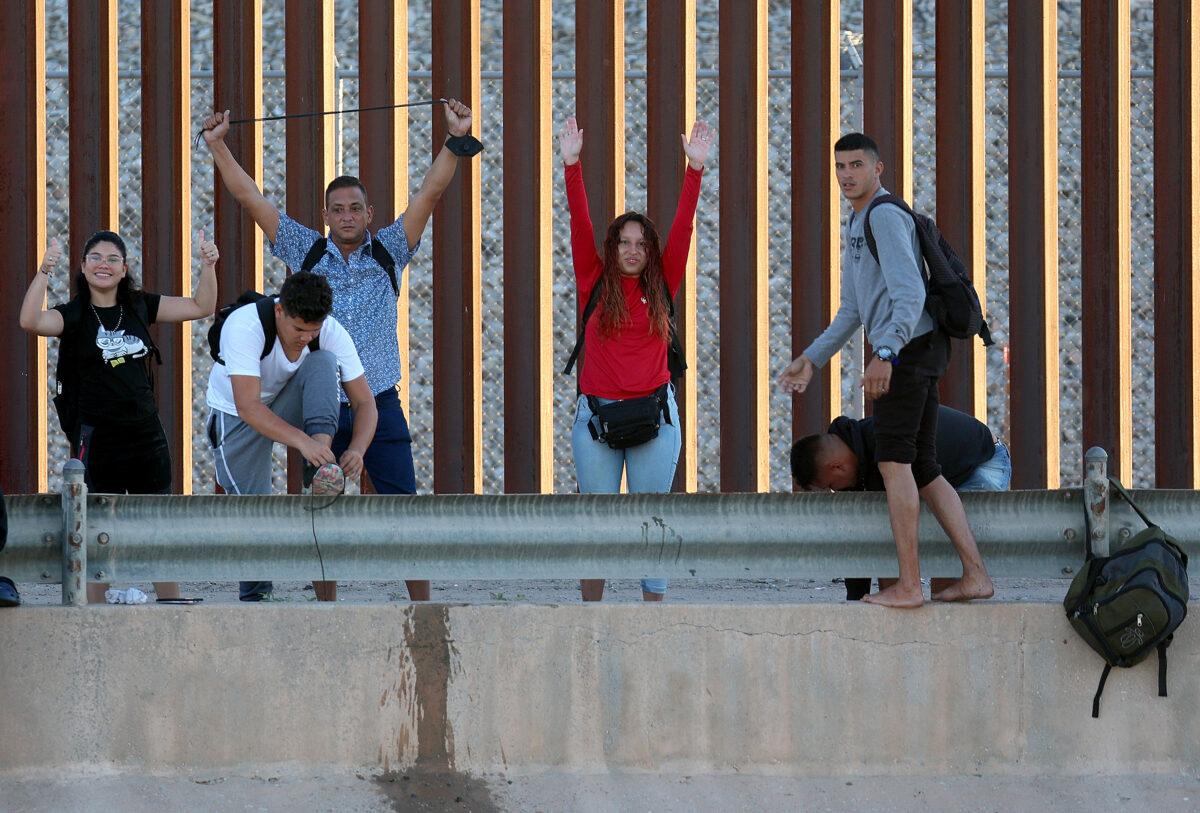 Venezuelan migrants gesture as they reach the U.S. border fence to turn themselves in to the U.S. Border Patrol after crossing the Rio Grande from Mexico in El Paso, Texas on September 22, 2022. (Joe Raedle/Getty Images)