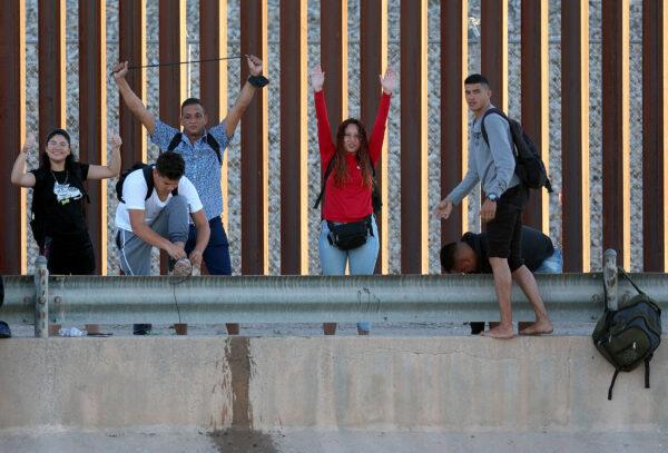 Asylum-seekers from Venezuela gesture as they reach the U.S. border fence to turn themselves in to the U.S. Border Patrol after crossing the Rio Grande from Mexico in El Paso, Texas, on Sept 22, 2022. (Joe Raedle/Getty Images)