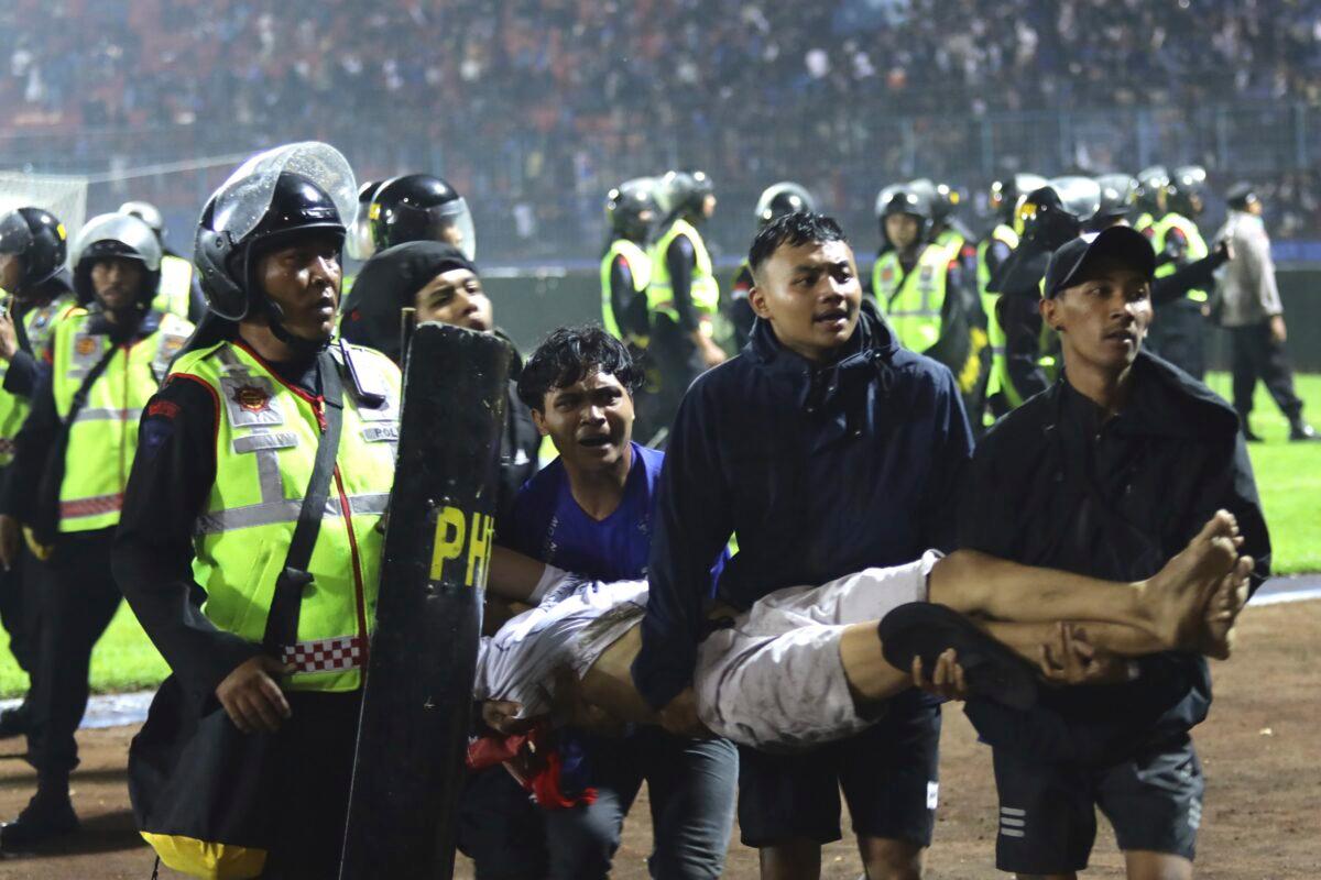 Soccer fans carry an injured man following clashes during a soccer match at Kanjuruhan Stadium in Malang, East Java, Indonesia, on Oct. 1, 2022. (Yudha Prabowo/AP Photo)
