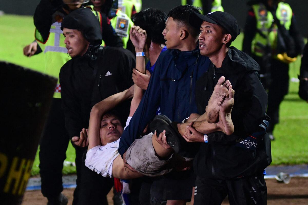 A group of people carry a man after a football match between Arema FC and Persebaya Surabaya at Kanjuruhan stadium in Malang, East Java, Indonesia, on Oct. 1, 2022. (STR/AFP via Getty Images)