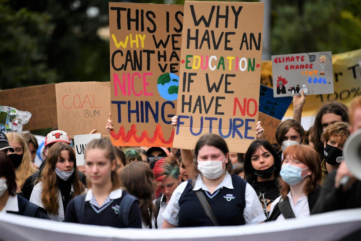 School students hold placards during a Climate School Strike protest at Treasury Gardens in Melbourne, Australia, on March 25, 2022. (AAP Image/Joel Carrett)