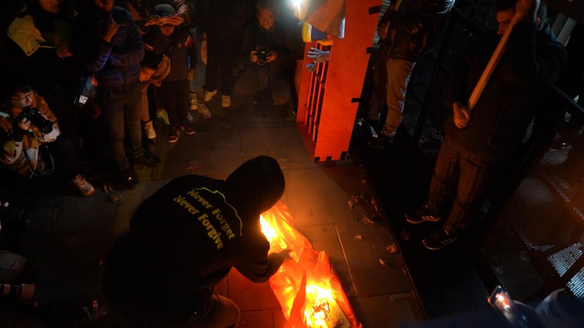 Protesters placed the Chinese National Flag on the ground at the entrance of the Chinese Embassy, and burned it with suspected faces and maggots in London, on Oct.1, 2022. (Chen Bin/The Epoch Times)