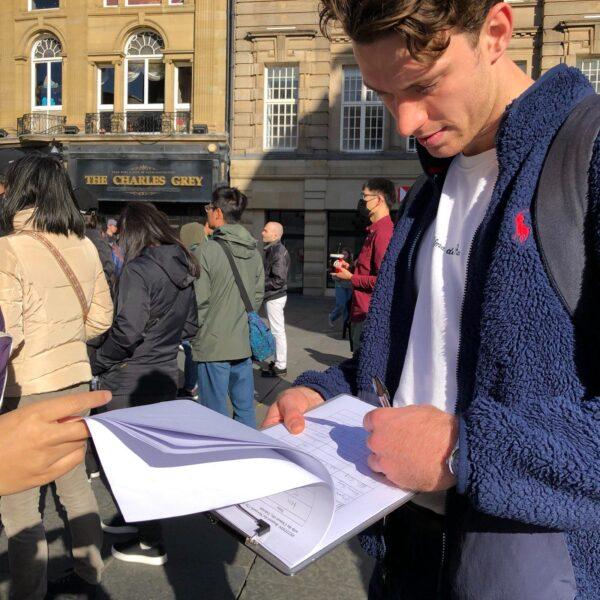 A British man signs a petition calling on UK city councils to sever ties with their sister cities in China at a rally against the CCP in Newcastle, England, on Oct. 1, 2022. (Ai Ping/The Epoch Times)