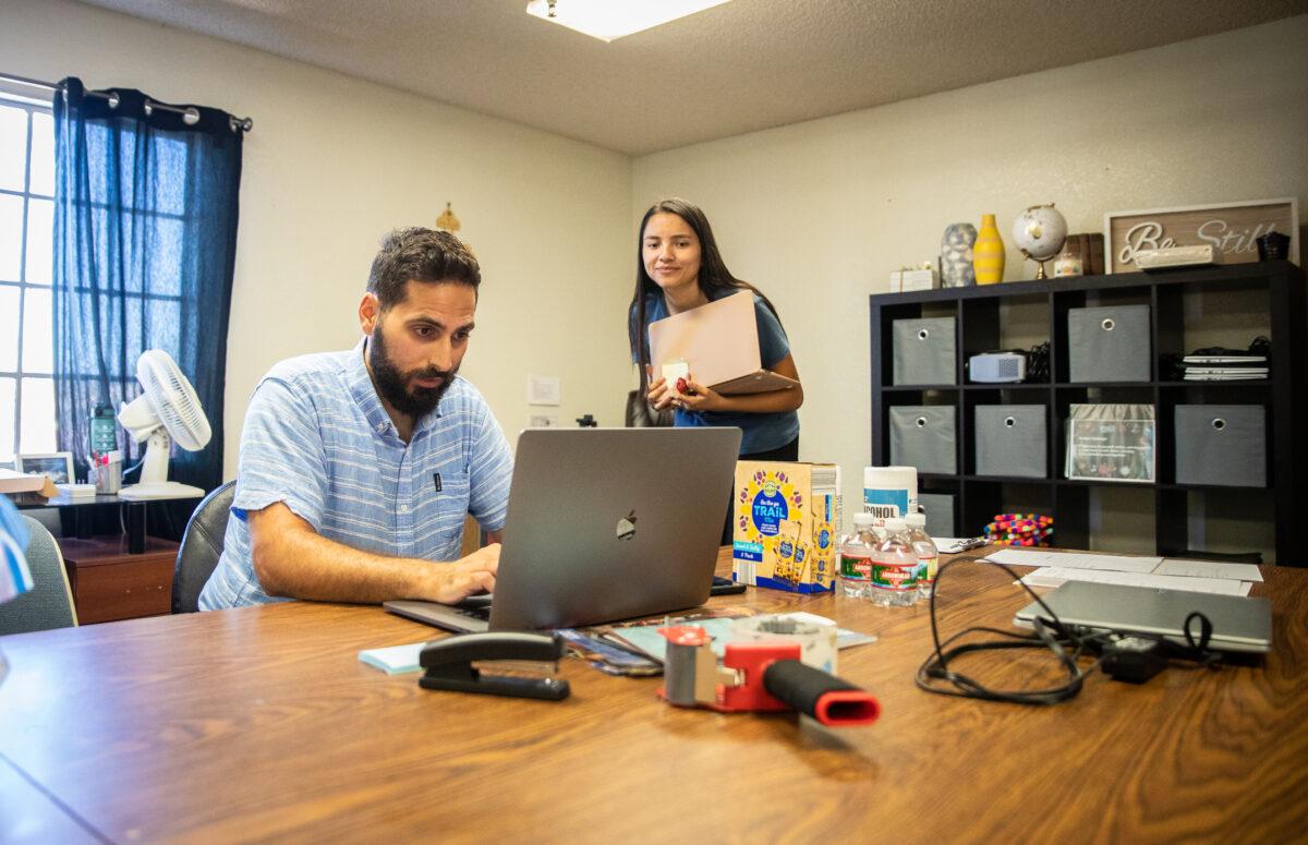 Voice of Refugees staff members Chris Khoury and Anna Diaz help with an online ESL class at the Voice of Refugees offices in Anaheim, Calif., on Sept. 21, 2022. (John Fredricks/The Epoch Times)