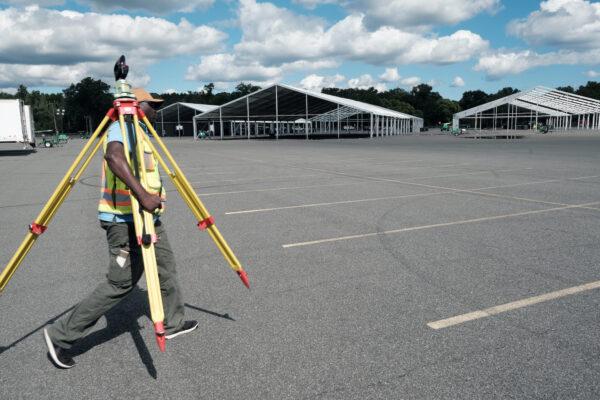 A land surveyor walks by large tents being constructed in a parking lot at Orchard Beach in the Bronx, N.Y., on Sept. 28, 2022. (Spencer Platt/Getty Images)