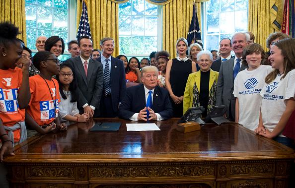 Former president Donald Trump sits surrounded by students, members of Congress, and members of his administration in the Oval Office, prior to signing a memorandum expanding access to STEM (science, technology, engineering, and math) education on Sept. 25, 2017. (Kevin Dietsch-Pool/Getty Images)