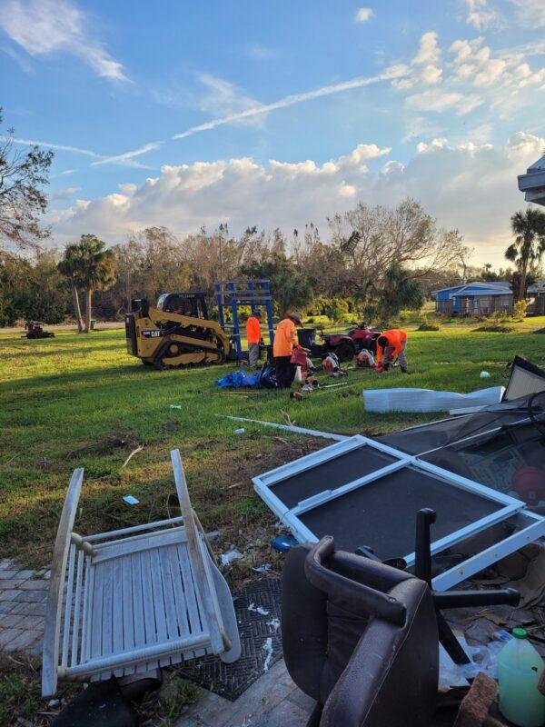Helpers sort through salvageable items from the hurricane-tossed debris spread across a yard on Riverside Drive in Punta Gorda, Fla. on Oct. 4, 2022. (Jann Falkenstern/The Epoch Times)