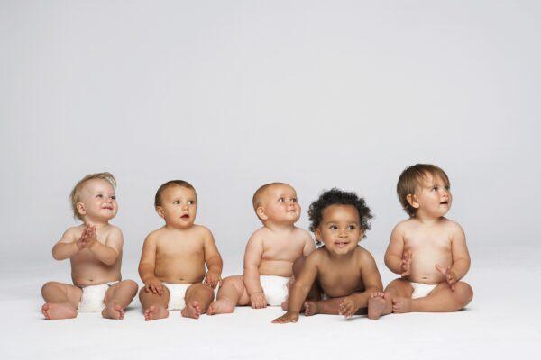 Five babies sitting on a white cloth. (sirtravelalot/Shutterstock)