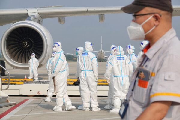Aviation ground crew wearing personal protective equipment working on an aircraft that flew in from abroad at the airport in Yantai, Shandong Province, China, on Sept. 18, 2022. (STR/AFP via Getty Images)