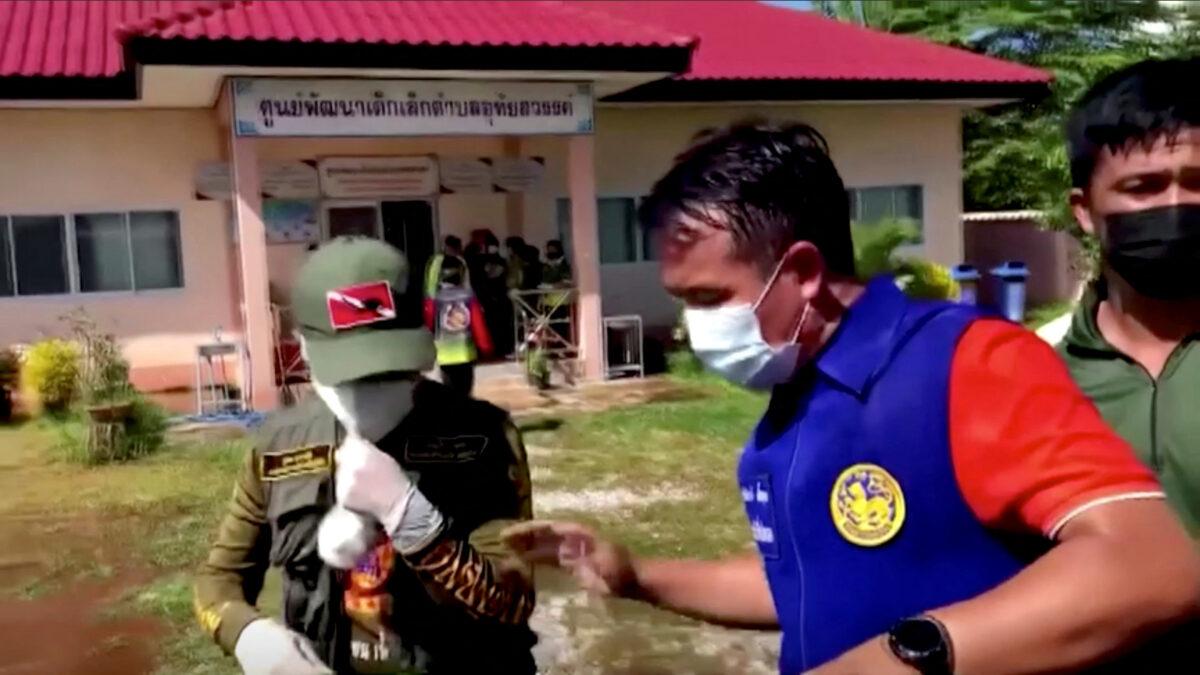 Officials and authorities guard the gate of a daycare center as people wait, after a rampage in Uthai Sawan, Nong Bua Lamphu Province, Thailand, on Oct. 6, 2022, in this screengrab taken from video. (TPBS/Reuters TV via Reuters)